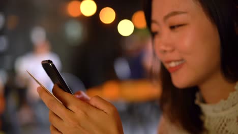 Smiling-young-asian-woman-shopping-on-mobile-phone-with-credit-card-payment