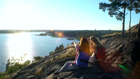 Happy-Female-Couple-Drinking-Champagne-on-a-High-Rock-in-the-Sunshine