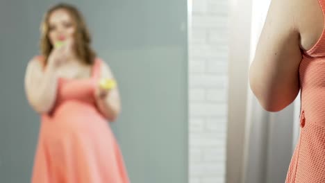 Übergewichtige-Frau-in-Kleid-Essen-Donuts-und-bewundern-Sie-ihr-Spiegelbild-im-Spiegel