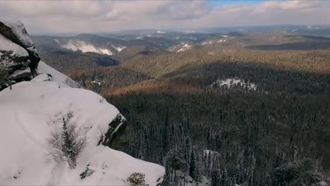 Aerial-view-of-a-rock-climber-climbing-a-steep-cliffs-during-a-sunny-winter-day.