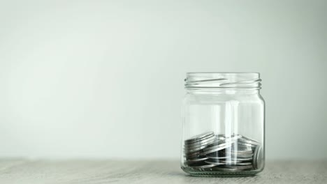 Close-up-Money-coin-falling-into-glass-jar-,-a-money-saving-,-donation-or-business-financial-growth-concept-,-4K-Dci-resolution-,-vintage-retro-color-tone