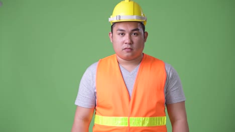 Trabajador-de-la-construcción-del-joven-guapo-asiáticos-con-sobrepeso-sobre-fondo-verde