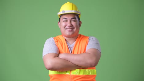 Trabajador-de-la-construcción-del-joven-guapo-asiáticos-con-sobrepeso-sobre-fondo-verde