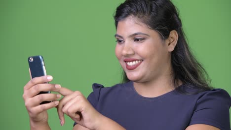 Young-overweight-beautiful-Indian-businesswoman-against-green-background