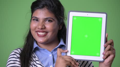 Young-overweight-beautiful-Indian-businesswoman-against-green-background