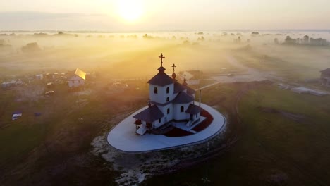 Luftaufnahmen-Video-der-kleinen-Dorfkirche-am-nebligen-Morgen.-Sonnenaufgangszeit.-Kyiv-Region,-Ukraine.-Fliegen-über-den-Fluss-Desna