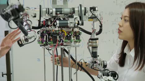 Electrónica-de-joven-ingeniero-equipo-colaborando-en-la-construcción-del-robot-en-el-taller.-Ingeniero-de-equipo-pone-en-marcha-proyecto-de-robot-juntos.-Personas-con-el-concepto-de-tecnología-o-innovación.