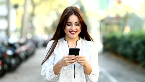 Mujer-caminando-hacia-cámara-usando-un-teléfono-inteligente