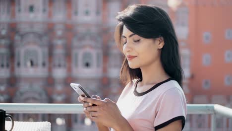 beautiful-woman-smiling-looking-at-the-camera-while-using-cellphone