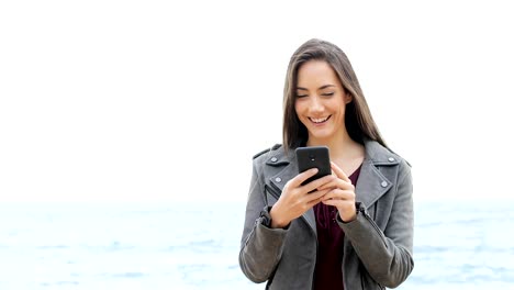 Glückliche-Frau-gehen-mit-Handy-am-Strand