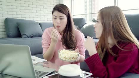 Lesbian-Asian-couple-using-laptop-making-budget-in-living-room-at-home,-sweet-couple-enjoy-love-moment-while-lying-on-the-sofa-when-relax-at-home.-Lifestyle-couple-relax-at-home-concept.