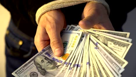 male-hand-bound-with-the-rope-holding-pile-of-money-american-dollar-bank-notes,-financial-rectrictions-concept