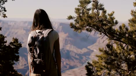 Slow-motion-back-view-happy-tourist-woman-hiking,-taking-smartphone-photo-of-epic-Grand-Canyon-park-mountain-scenery.