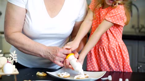 Mädchen-dekoriert-Osterkekse-mit-Großmutter