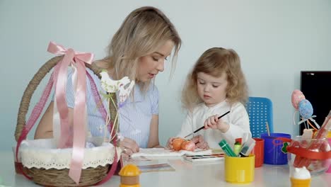 Mother-and-her-little-daughter-painting-Easter-eggs