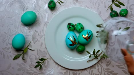 Hand-removes-a-glass-dome-from-a-plate-with-green-easter-eggs