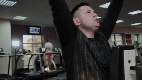 Cheerful-fat-man-performs-a-wrong-exercise-in-the-gym.-For-the-first-time-in-a-fitness-club