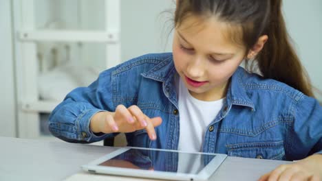 feliz-niña-pequeña-tocando-la-pantalla-de-la-tableta-mientras-juega-juegos-en-línea