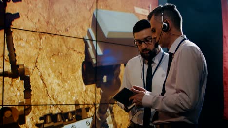 Two-technicians-watching-screen-in-control-room