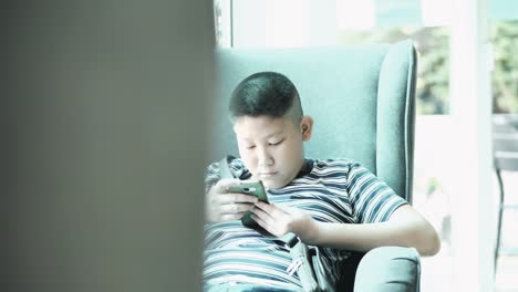 Young-teenager-playing-game-on-smartphone-in-cafe