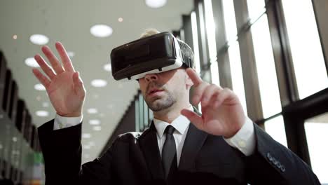 Panning-medium-shot-of-modern-middle-aged-businessman-in-VR-headset,-exploring-analytical-data-visualized-in-virtual-reality-standing-in-sunlight