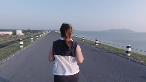 Asian-women-jogging-in-the-street-in-the-early-morning-sunlight-at-water-storage-Pa-Sak-Jolasid-Dam.-concept-of-losing-weight-with-exercise-for-health.-Rear-View