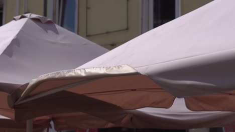 Sunshade-over-the-tables-of-the-summer-open-area-of-the-restaurant-on-the-city-street.-Close-up