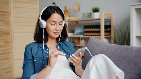 Slow-motion-of-pretty-girl-listening-to-music-in-headphones-using-smartphone