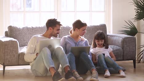 Happy-modern-family-sit-on-floor-talking-using-devices