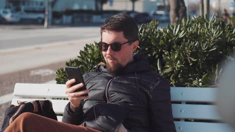 Man-is-browsing-by-smartphone-sitting-outdoors