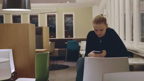 Woman-sitting-alone-in-cafe-and-using-mobile