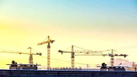 silhouette-of-cranes-working-on-construction-site-on-sunset-sky-background.