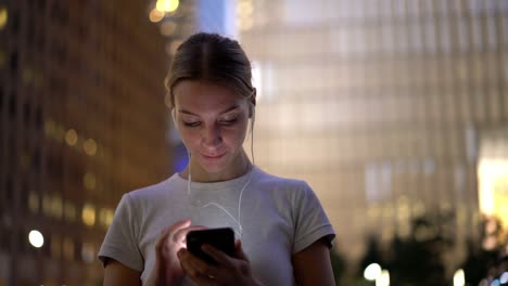 Mujer-joven-disfrutando-de-la-música-en-los-auriculares-modernos,-canciones-electrónicas-de-escucha-femenina-positivas-en-auriculares-conectados-a-teléfonos-inteligentes