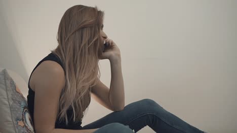 Beautiful-girl-with-a-mobile-phone-resting-on-a-sofa-at-home.-A-blonde-girl-is-talking-on-a-cell-phone.