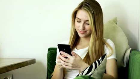 Young-smiling-woman-using-smartphone,-texting-on-mobile-phone-in-modern-cafe.-4K