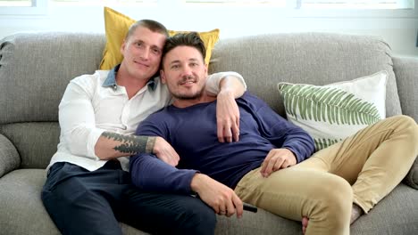 Gay-couple-relaxing-on-couch-watching-tv.-Using-remote-control.