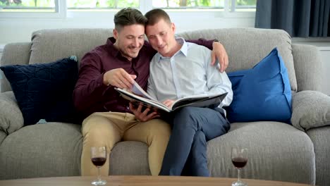 Gay-couple-relaxing-on-couch.-Wide-shot.-Hugging-each-other.