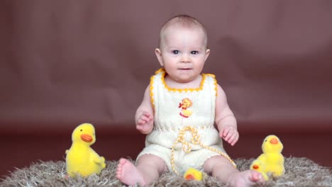 Lindo-niño-pequeño-niño,-jugando-con-huevos-de-pascua-de-colores-y-patos-decorativos-pequeños,-tiro-aislado,-fondo-beige