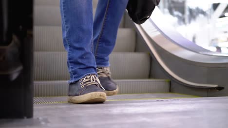 Los-pies-de-la-gente-bajan-por-el-ascensor-de-la-escalera-en-el-centro-comercial.-Pies-de-comprador-en-Escalera-Saltadora-en-el-Centro-Comercial