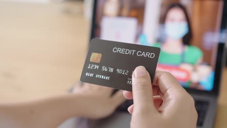 Close-up-consumer-woman's-hand-holding-credit-card-making-e-bank-online-payment-for-purchase-in-online-website-store-with-laptop-computer.-Ecommerce-website-payments.-new-normal-digital-lifestyle