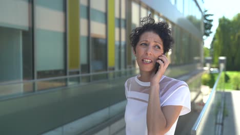 Zoom-in-close-up-shot-of-smiling-female-entrepreneur-talking-on-mobile-phone-outside-office-in-city