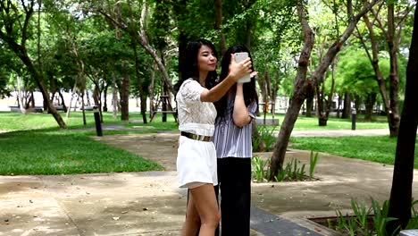 Female-friends-taking-photo-with-cellphone-in-garden