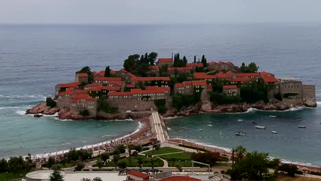 Insel-Sveti-Stefan-in-Montenegro.-Schuss-zu-verkleinern.-Saint-Stephen-Montenegro-Adria-Küste-Linie-rosa-Sandstränden-Boot-auf-blauen-Meerwasser.-Resort-für-Rich-mans.-Luftaufnahme,-Insel-Landenge.