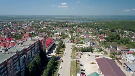 big-city-near-river,-aerial-view,-multicolor-roof-of-houses,-sunny-summer-day,-clear-blue-sky-with-small-clouds