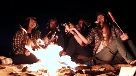 pareja-joven-bebiendo-bebidas-y-haciendo-brindar-cerca-del-fuego-en-el-bosque-de-noche,-los-amantes-de-beben-alcohol-y-hace-tostar-cristal-al-aire-libre,-chico-con-chica-vítores-cerveza-en-viaje-campamento-en-el-bosque