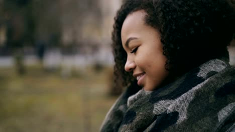 Closeup-tilt-up-shot-of-mixed-race-student-girl-using-smartwatch-and-smiling-near-univercity