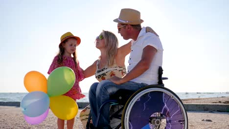 happy-mom-and-daughter-stand-near-dad-disabled-in-backlight,-family-talk-about-pregnancy,-parents-tell