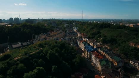 Zángano-de-la-cámara-se-mueve-bajo-techos-de-edificios-en-antigua-europeas-callejuelas-con-casas-de-colores-y-los-peatones-al-atardecer-4K