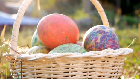 Close-up-of-basket-with-colourful-a-easter-eggs-on-grass-in-sunshine-background