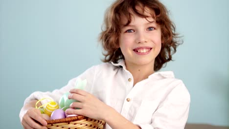 Un-niño-tiene-un-conejito-de-Pascua-y-un-conjunto-de-huevos-de-Pascua-decorativos.-El-muchacho-se-ríe-alegremente.-Cámara-lenta